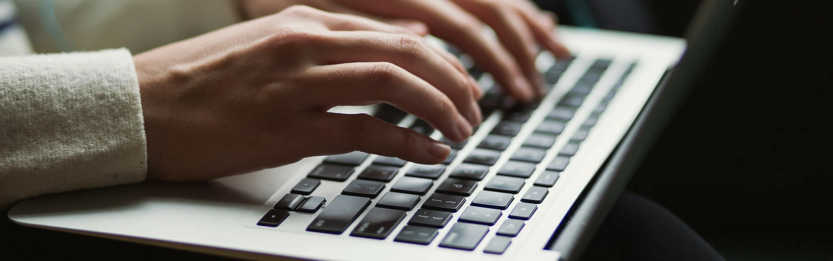 Handen typen een artikel op een laptop